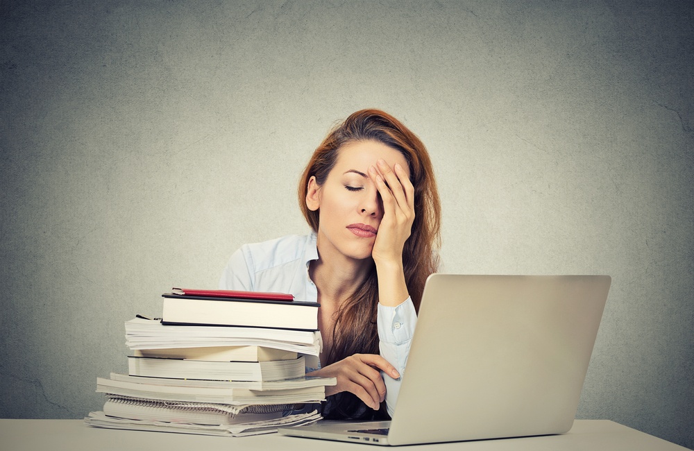 Too much work tired sleepy young woman sitting at her desk with books in front of laptop computer isolated grey wall office background. Busy schedule in college, workplace, sleep deprivation concept-1.jpeg